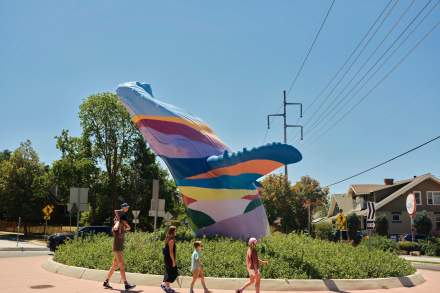 Family walking on a round-a-bout. The center of it has a whale sculpture painted in rainbow colors