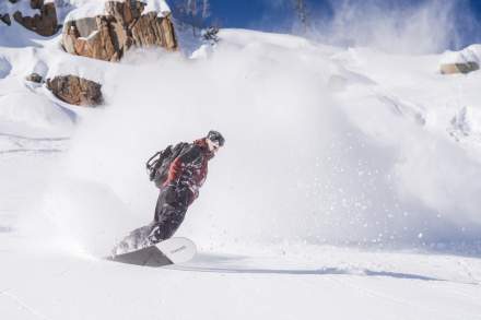 A snowboarder that is snowboarding through powder at Brighton Resort.