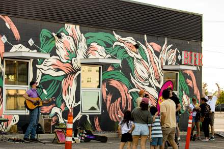 People enjoying Mural Fest in South Salt Lake (333 W 2100 S). The people are looking at Artist Angie Jerez's mural.