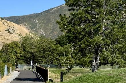 Paved trail path with park and trees leading toward hills and mountains