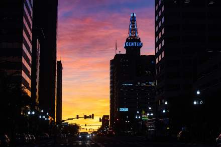 Vibrant sunset with gold, orange, pink, and purple clouds with a silhouette of the Walker Center and other downtown Salt Lake buildings