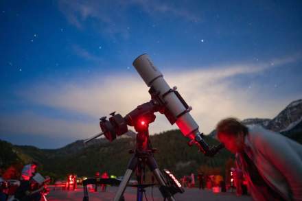 Woman looking in a telescope at a dark blue night sky