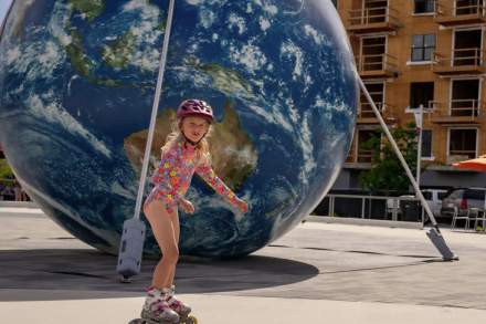 A girl roller skating at Millcreek commons in front of a blow-up globe of the Earth.