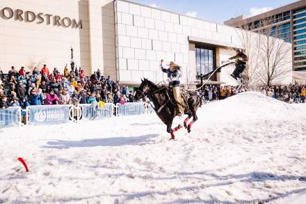 Women on horse drags man skiing over a man-made ski jump. The man is being pulled by rope by the woman on a horse on West Temple Street in front of Nordstrom's in City Creek Center.