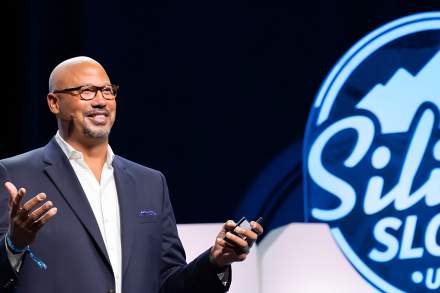Man standing in front of a Silicon Slopes Utah logo like he is addressing an audience