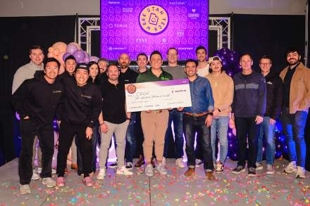 Group of people posing with a check after winning a pitch.