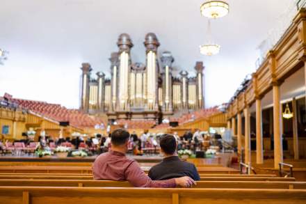 Two men sitting in the benches at the tabernacle with the historic organ in the background