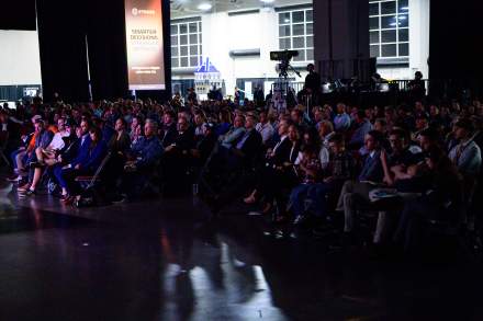 Audience members watching the main stage at a conference in the Salt Palace Convention Center.