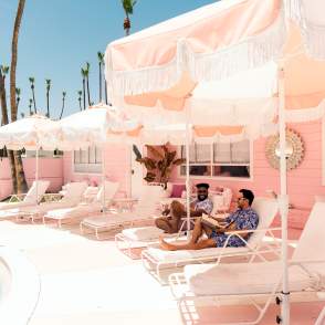 Two guys sitting in lounge chairs at the pink Trixie motel in Palm Springs