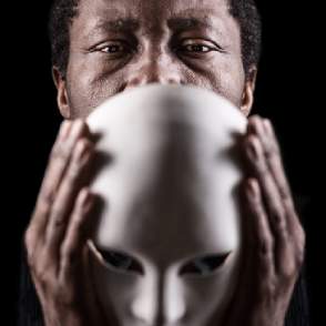 African American gentleman holding a white mask for plays and performing arts