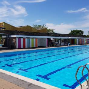 An outdoor swimming pool with changing facilities in background