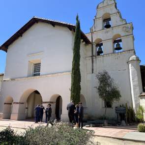 San Juan Bautista Mission. People stand in front of the Mission entryway and Bell Tower.