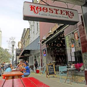 Red picnic tables on the sidewalk outside Roosters restaurant