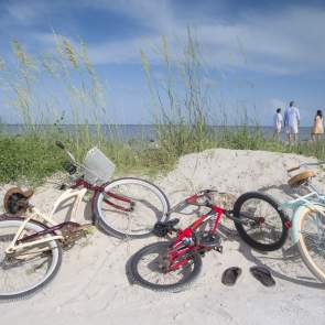 three bicycles laying on a sand dune on the beach