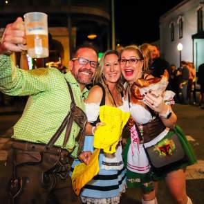 Two women and a man holding a beer bug and a pretzel