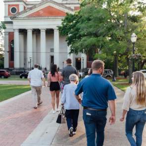 Men and women walk together on a sidewalk towards a large church