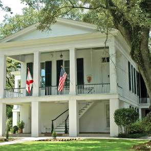 white two-story building with four columns and two flags
