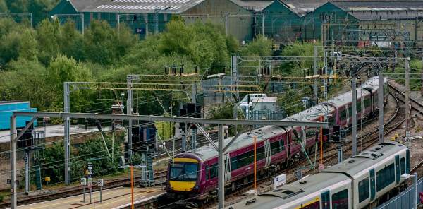 Wide view photograph of train tracks coming into the city, with a West Midlands Railway train on the tracks