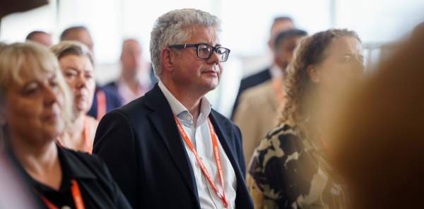 A group of people in business dress listen to a speaker, who is not pictured.