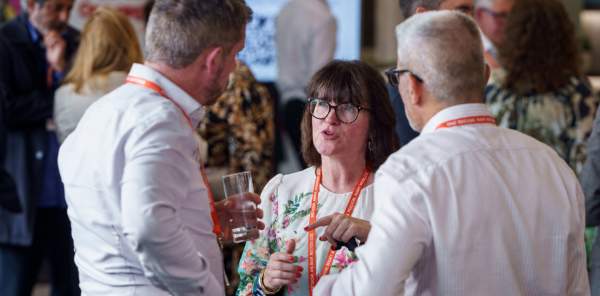 Three businesspeople converse amidst a networking event.
