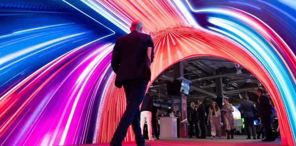 A tunnel of lights leading into the Regional Investment Summit 2025 with a man in a suit walking through