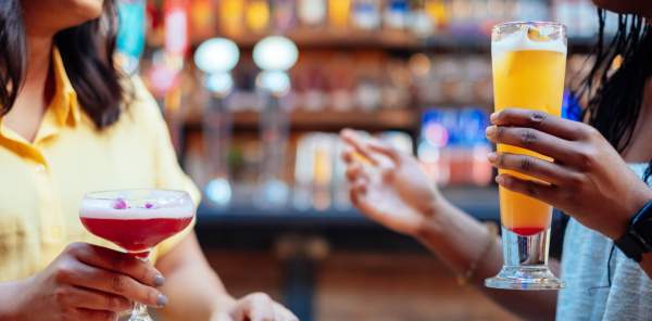 Two friends share cocktails in a bar in Digbeth