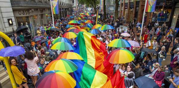 Birdseye view of the crowd carrying rainbow umbrellas and a giant rainbow flag at Birmingham Pride Festival