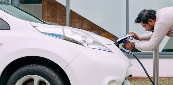 A man plugs in an electric car to charge