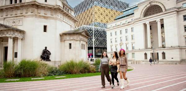 Three ladies walking at the back of Centenary Square with the Library of Birmingham in the background.
