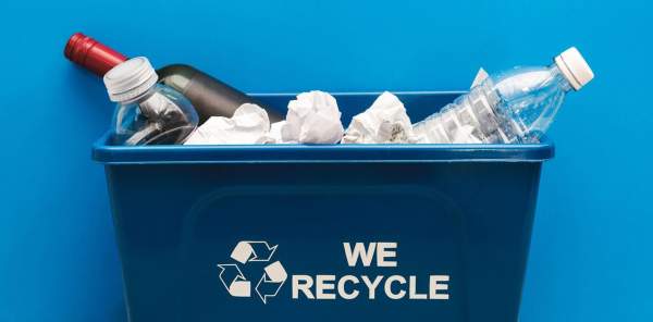 Recycling bin with filled with paper, glass and plastic bottles