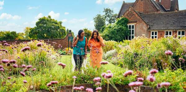 Two ladies looking at spring flowers in front of Winterbourne House and Garden