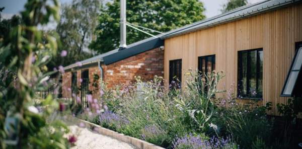 A path, a storehouse and some wild flowers growing at The Farm