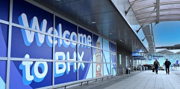 Outside of Birmingham International Airport a wall sign says Welcome to BHX
