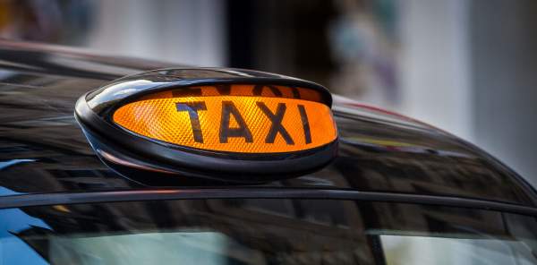 Lit up taxi sign on top of a black cab