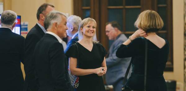 Partners and stakeholders talk at a black tie investment event.