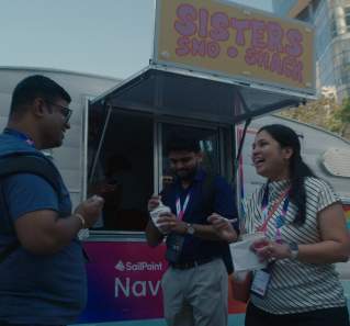 Three meeting attendees smiling and talking next to a food truck.