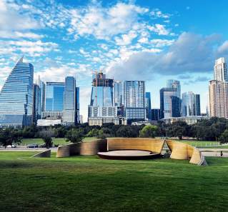 Downtown Austin skyline set behind greenspace and 3D printed stage.
