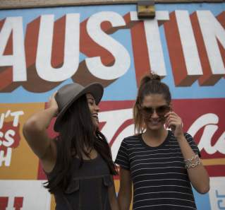 Two girls laughing in front of Austin mural