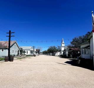 Open backlot with gravel road, small buildings and a church, as an example of a western film set.