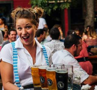 Woman wearing a white shirt and blue suspenders holding a platter of beer at Banger's Oktoberfest