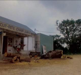 Texas Chainsaw Massacre 2 screengrab, showing the exterior of an old building with a sign reading Cut Rite Chainsaws