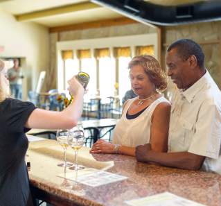 couple watching as woman pours samples of wine at Inwood Estates winery in Fredericksburg Texas