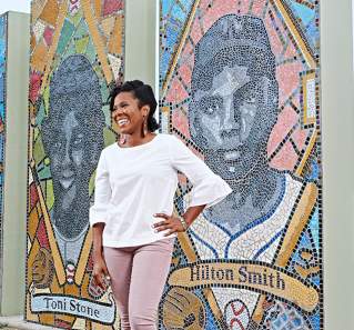 Nefertitti Jackmon stands in front of the mosaic of iconic Black baseball players at Downs Mabson Field in East Austin Texas
