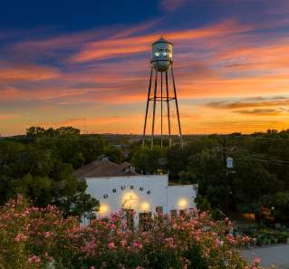 Aerial photo of Gruene Hall with a colorful sunset and a metal water tower in the back.