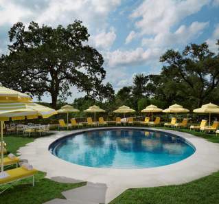 Commodore Perry Estate Pool surrounded by yellow chairs and umbrellas in Austin Texas