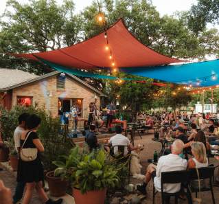 Photo of people sitting on at outdoor patio at Radio Coffee & Beer watching a live band performing on stage.