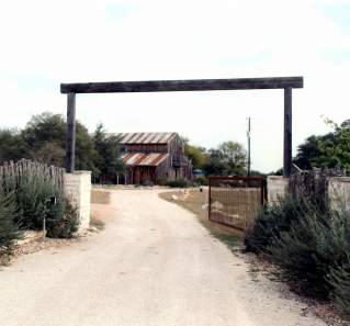Gravel road leading to a ranch property with a tin-roof barn.