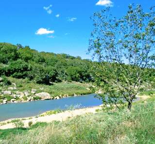 Hill Country setting with lush greenery along the banks of a bright blue river.