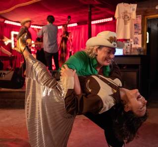 Two women in Western attire country dancing in a dance hall.