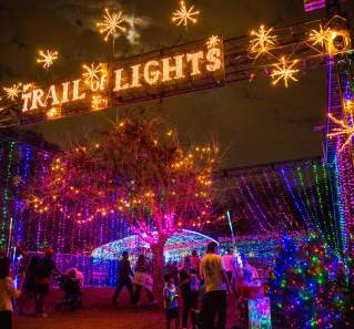 Image from a low perspective of the large illuminated sign stating "Trail of Lights" at the entrance to the event.